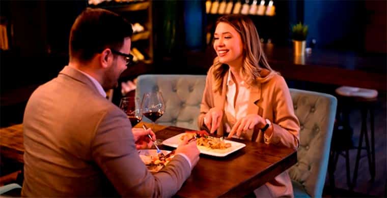 Mesa de restaurante com casal sorrindo e bebendo vinho.