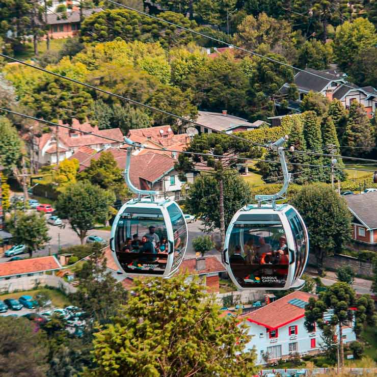 Imagem de teleférico em meio à natureza exuberante, com casas ao fundo. Ideal para explorar o Parque Nacional.